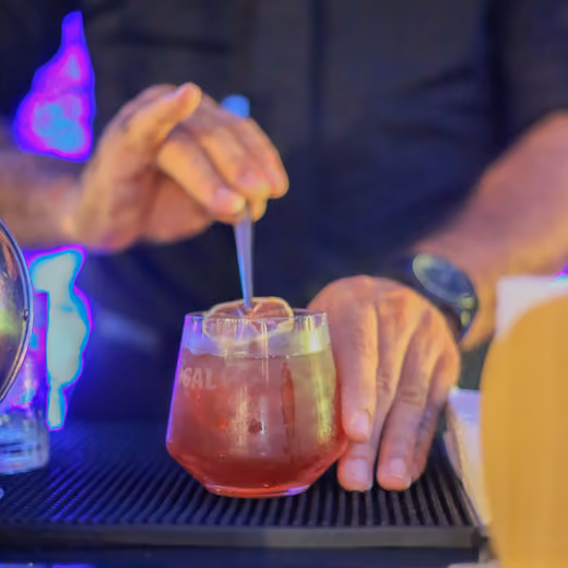 Bartender preparando un cóctel con naranja deshidratada