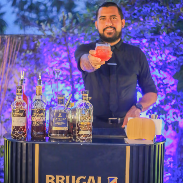 Bartender de Casa Cora ofreciendo un cóctel junto a las botellas