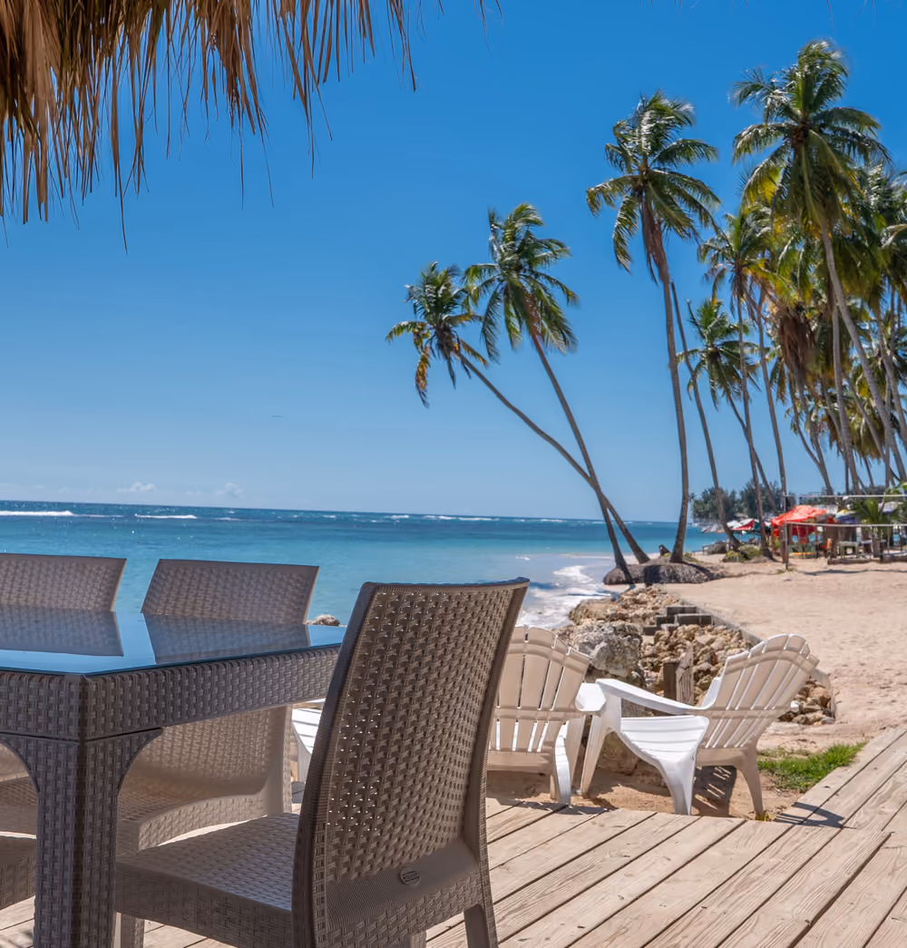 Terraza de madera con mesas frente a la playa de Juan Dolio
